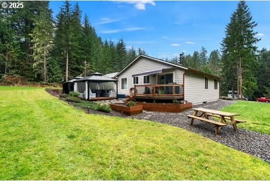 rear view of property featuring a gazebo, a lawn, and a wooden deck