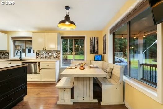 kitchen with backsplash, decorative light fixtures, white cabinetry, and light hardwood / wood-style floors