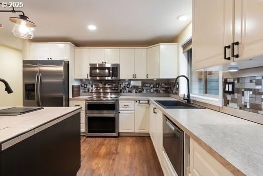 kitchen with hanging light fixtures, sink, white cabinets, and stainless steel appliances