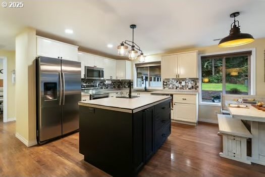 kitchen with white cabinets, a kitchen island, hanging light fixtures, and appliances with stainless steel finishes