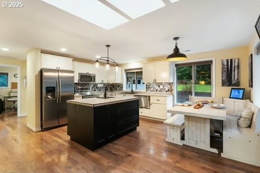 kitchen featuring white cabinets, a kitchen island, hanging light fixtures, and appliances with stainless steel finishes