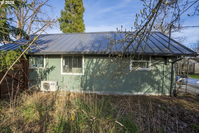 view of side of property featuring a standing seam roof, ac unit, and metal roof