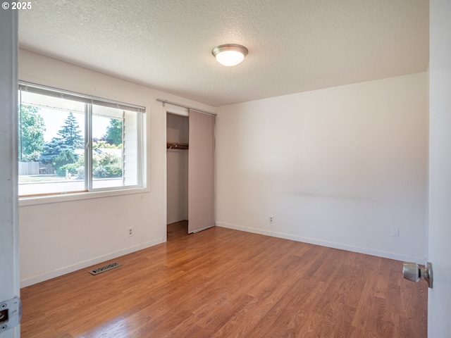 841 NE Kathryn St, Hillsboro, OR 97124 - unfurnished bedroom featuring light wood finished floors, a textured ceiling, baseboards, and a closet