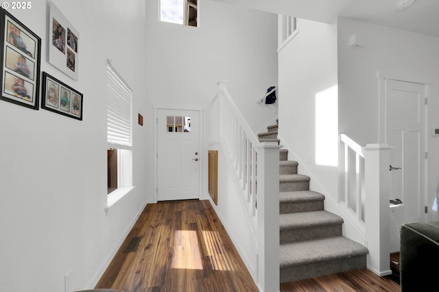 stairs with a towering ceiling and wood-type flooring