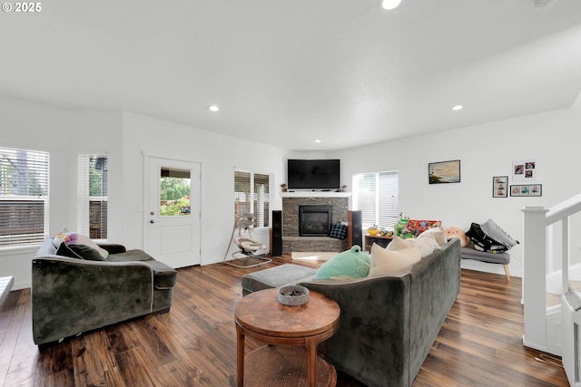 living room with a stone fireplace and dark wood-type flooring