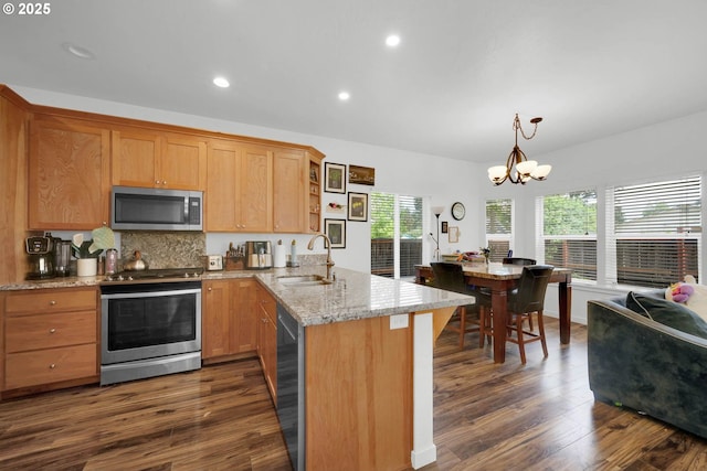 kitchen featuring dark wood-type flooring, sink, an inviting chandelier, appliances with stainless steel finishes, and kitchen peninsula