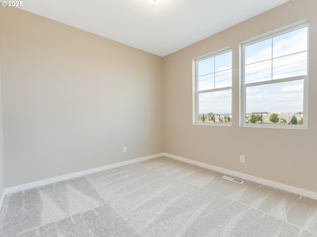 spare room with light carpet and baseboards