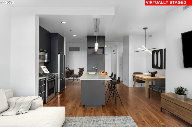949 NW Overton St Unit 1304, Portland, OR 97209 - kitchen featuring stainless steel appliances, a sink, light countertops, a breakfast bar area, and dark cabinets