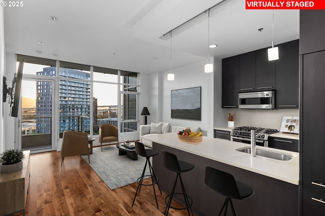 949 NW Overton St Unit 1304, Portland, OR 97209 - kitchen featuring stainless steel appliances, dark cabinetry, a sink, a breakfast bar, and wood finished floors