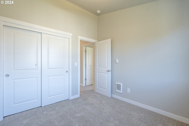 unfurnished bedroom with light colored carpet and a closet