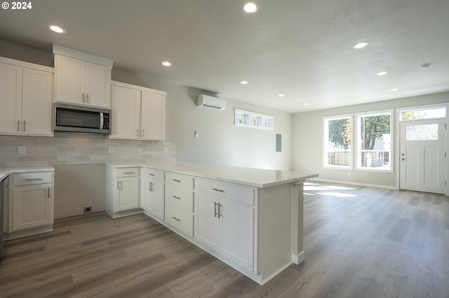 kitchen featuring kitchen peninsula, white cabinets, light hardwood / wood-style flooring, and tasteful backsplash