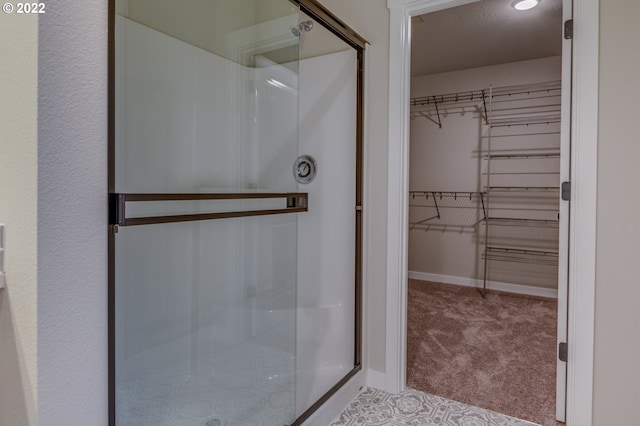 full bathroom featuring a walk in closet, baseboards, and a shower stall