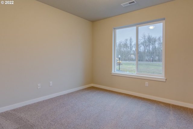 carpeted empty room featuring baseboards and visible vents