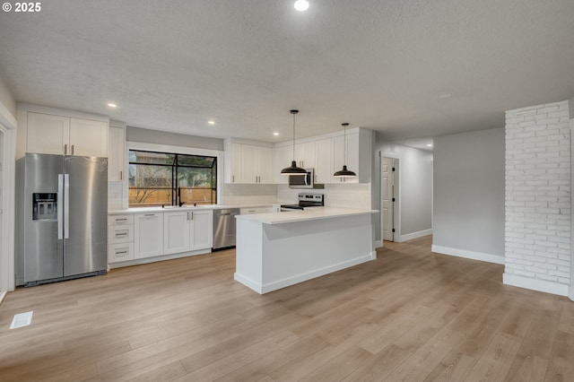 kitchen with white cabinets, decorative light fixtures, light hardwood / wood-style flooring, backsplash, and stainless steel appliances