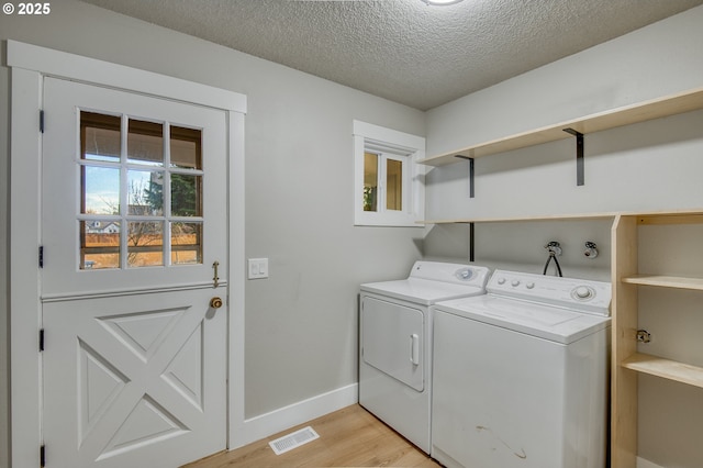 laundry room featuring washer and dryer, a textured ceiling, and light wood-type flooring