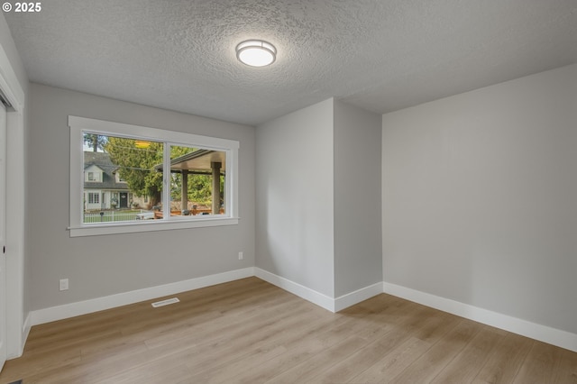 unfurnished room with a textured ceiling and light hardwood / wood-style flooring