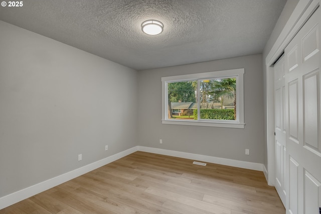 unfurnished bedroom featuring a closet, light hardwood / wood-style flooring, and a textured ceiling