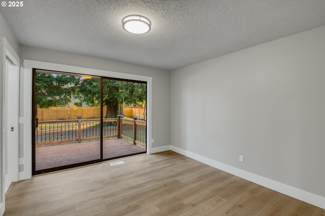 empty room featuring light wood-type flooring and a textured ceiling