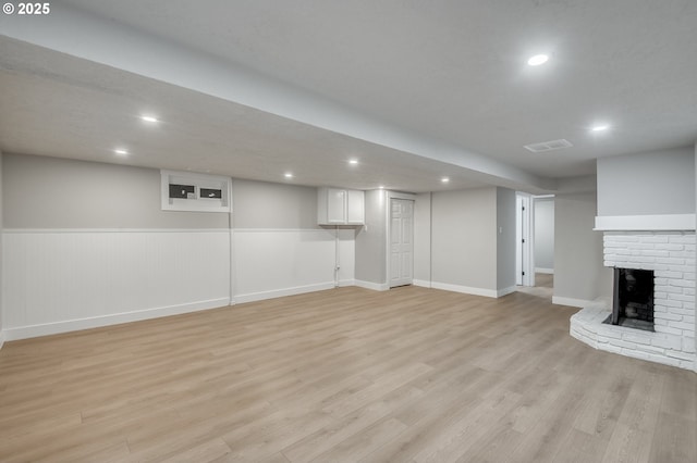 basement featuring a fireplace and light hardwood / wood-style flooring