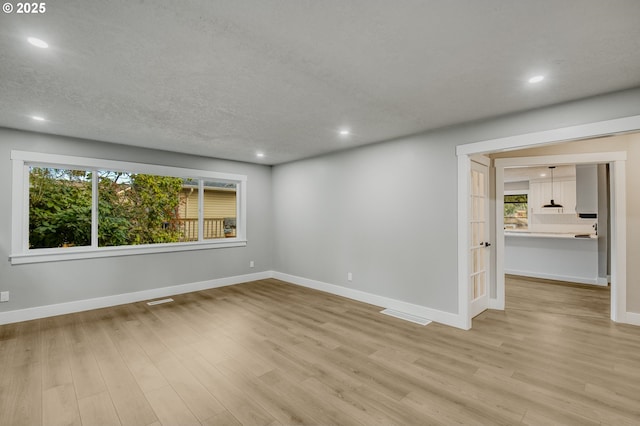 empty room with light hardwood / wood-style floors and a textured ceiling