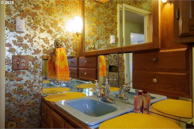 bathroom with wallpapered walls and a sink