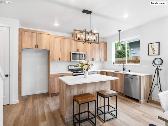 kitchen featuring a sink, stainless steel appliances, a kitchen island, and light countertops