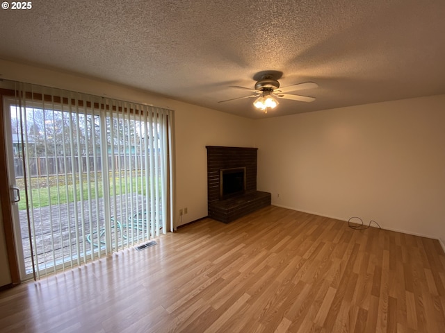 845 Waite St, Eugene, OR 97402 - unfurnished living room featuring light wood-type flooring, ceiling fan, a textured ceiling, a brick fireplace, and baseboards