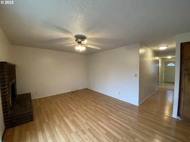 845 Waite St, Eugene, OR 97402 - unfurnished living room with light wood finished floors, a ceiling fan, a textured ceiling, and a brick fireplace