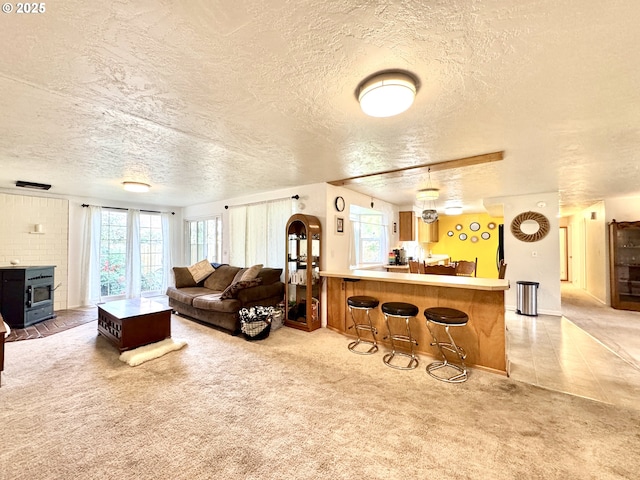 living room featuring light tile patterned floors, a wood stove, light carpet, and a textured ceiling