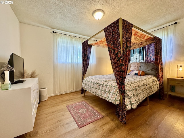 bedroom with light wood-style flooring, multiple windows, and a textured ceiling