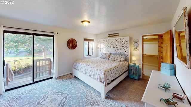 carpeted bedroom with a textured ceiling, access to exterior, and a walk in closet