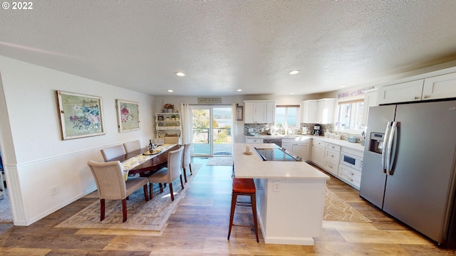 kitchen with plenty of natural light, white cabinetry, a kitchen island, and stainless steel fridge