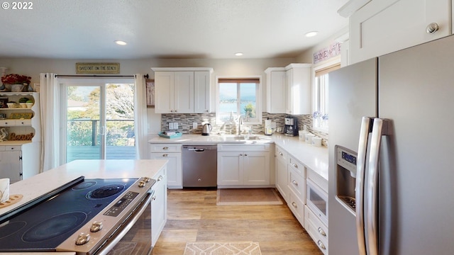 kitchen with white cabinets, sink, stainless steel appliances, and light hardwood / wood-style floors