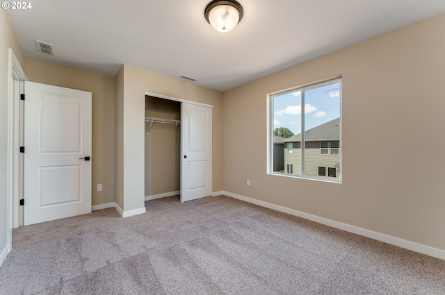 unfurnished bedroom featuring light carpet and a closet