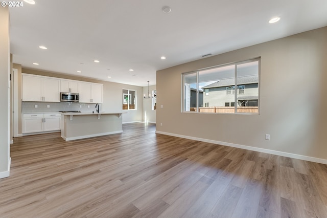 unfurnished living room featuring sink and light wood-type flooring