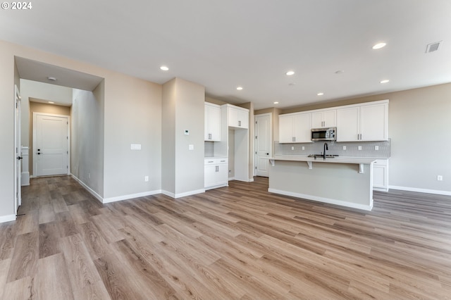 unfurnished living room featuring light hardwood / wood-style floors and sink