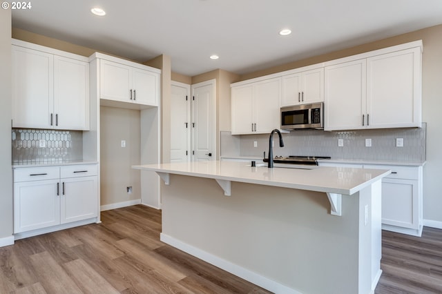 kitchen featuring white cabinetry, sink, and an island with sink