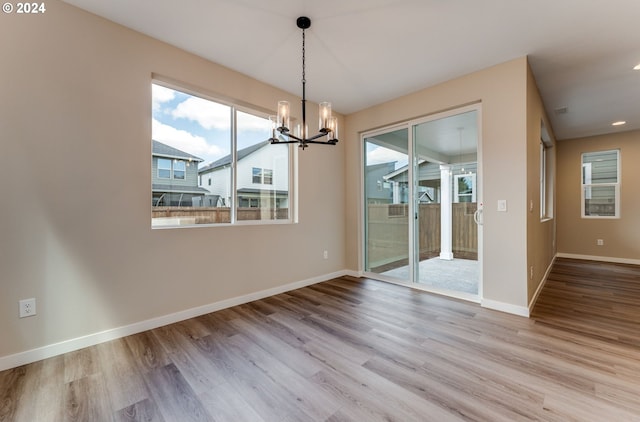 unfurnished dining area with an inviting chandelier and light hardwood / wood-style flooring