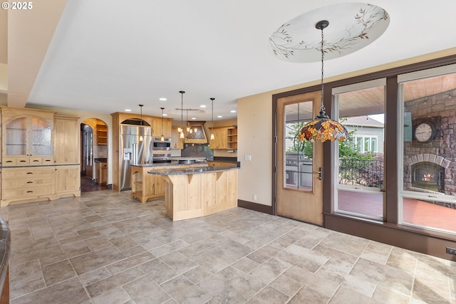 632 W T St, Washougal, WA 98671 - kitchen featuring high end fridge, a center island, a kitchen breakfast bar, light stone finish flooring, and arched walkways