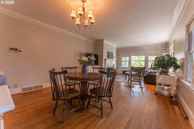 dining area featuring visible vents, crown molding, wood finished floors, baseboards, and a chandelier