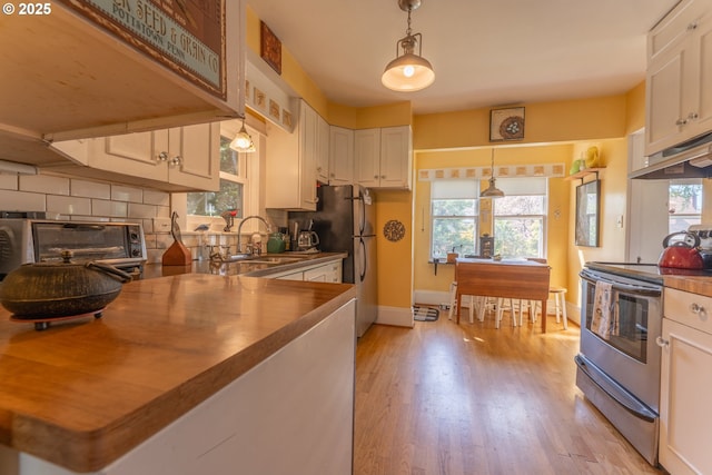 kitchen with a healthy amount of sunlight, under cabinet range hood, a sink, light wood-style flooring, and stainless steel appliances