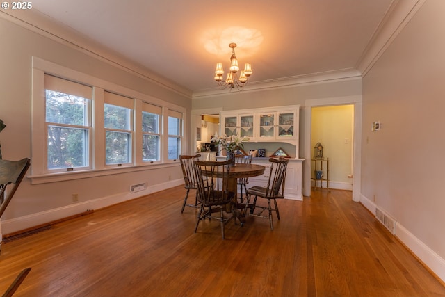 dining area featuring baseboards, an inviting chandelier, ornamental molding, and light wood-style flooring