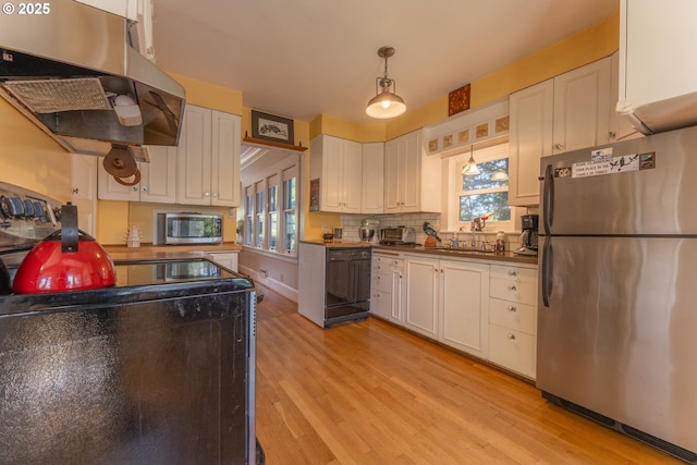 kitchen with dark countertops, light wood-style flooring, range hood, and stainless steel appliances
