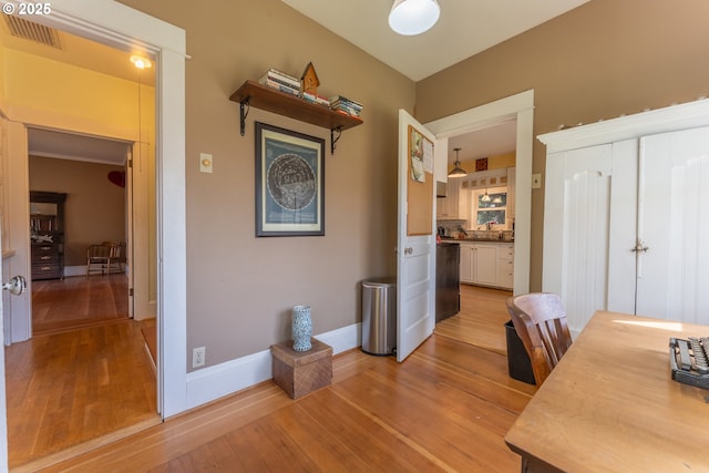 interior space featuring baseboards, visible vents, and light wood-type flooring