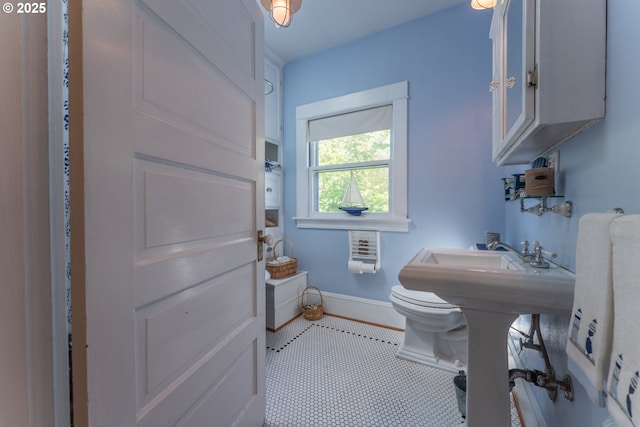 half bathroom featuring toilet, baseboards, and tile patterned floors