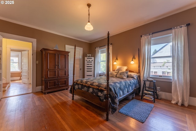 bedroom with baseboards, ornamental molding, multiple windows, and hardwood / wood-style floors
