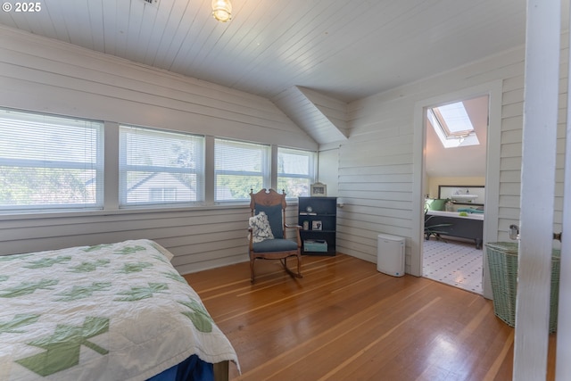 bedroom with wood-type flooring, wooden walls, and multiple windows