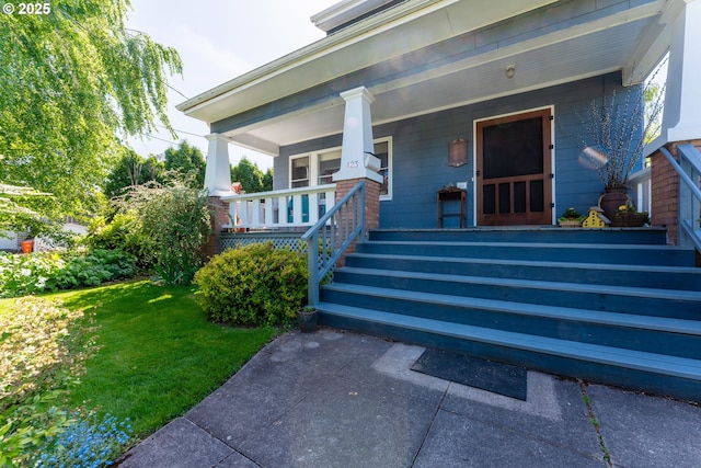 doorway to property featuring covered porch and a yard