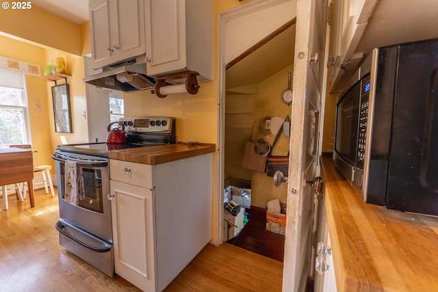 kitchen featuring electric range, white cabinets, light wood-style floors, wood counters, and under cabinet range hood