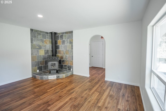 28788 Gimpl Hill Rd, Eugene, OR 97402 - unfurnished living room featuring baseboards, a wood stove, wood finished floors, recessed lighting, and arched walkways